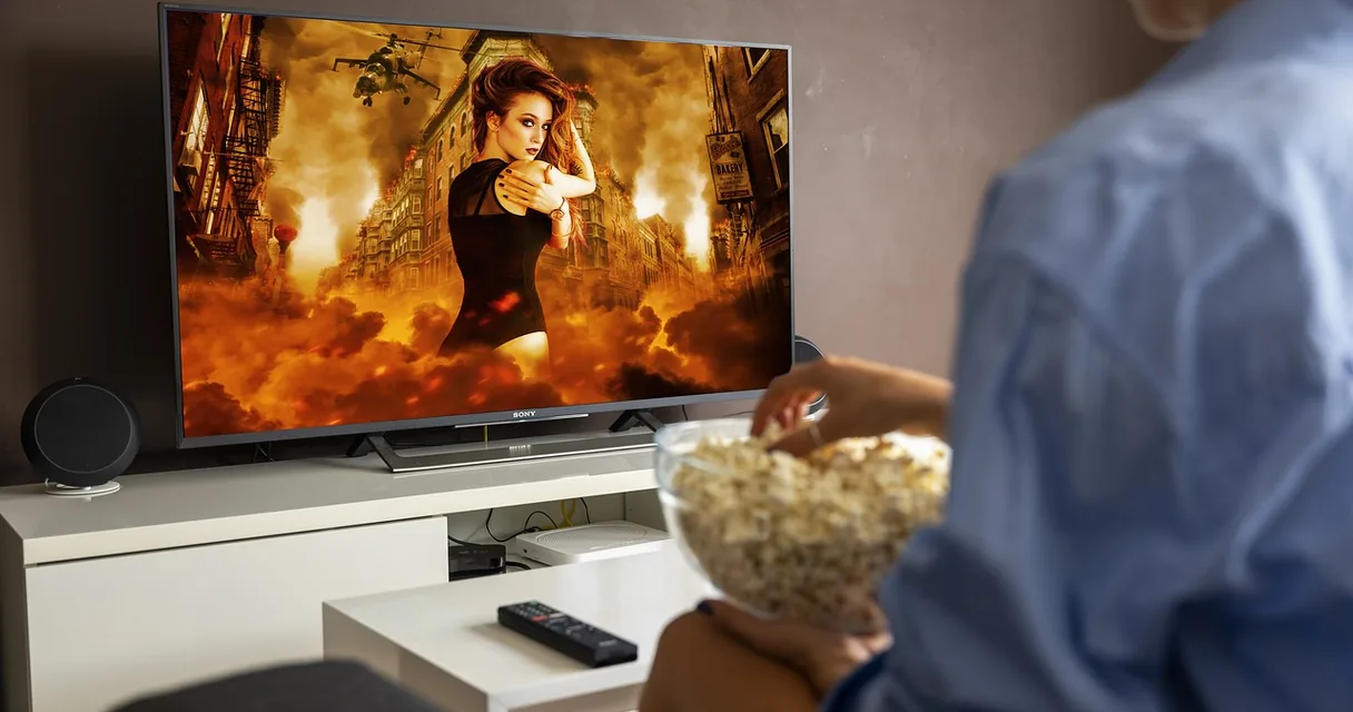 Pessoa com pipoca assistindo filme na TV durante o teste IPTV grátis da IPTV Grátis